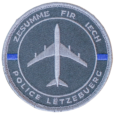 Abzeichen der Polizei Luxemburg mit einem Flugzeug und dem Motto "Zesumme fir Iech".