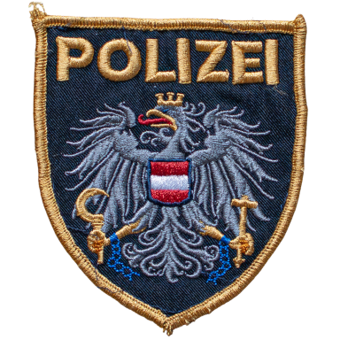 Wappen der Polizei mit einer goldenen Schrift und einem Adler, der Symbole hält.