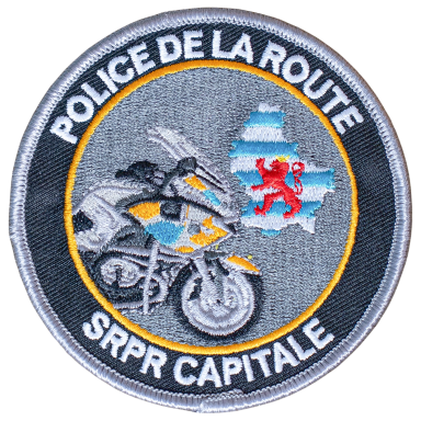 Abzeichen der Polizei mit Motorrad und Wappen eines Bären auf einem Kartenhintergrund.