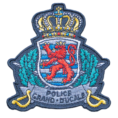 Wappen der Polizei Grand-Ducale mit Löwen und Krone, umgeben von Eichenblättern.
