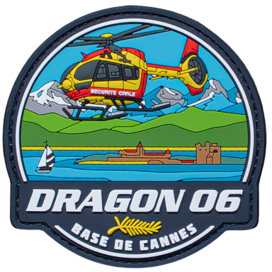 Helikopter fliegt über das Wasser mit Bergen und einer Burg im Hintergrund.