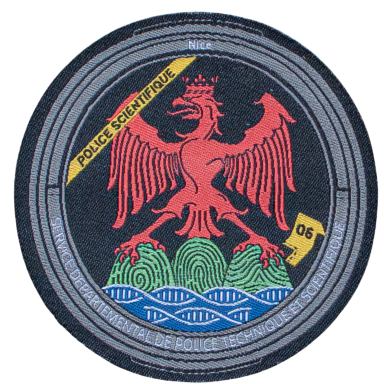 Rundes Emblem mit rotem Adler, Wellen und grünen Hügeln, begleitet von Text.