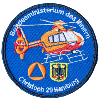 Wappen des Bundesministeriums des Innern mit einem Hubschrauber und dem Text „Christoph 29 Hamburg“.