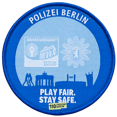 Blauer Polizei-Abzeichen aus Berlin mit Brandenburger Tor und dem Slogan „Play fair. Stay safe.“