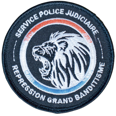 Abzeichen der Justizpolizei mit Löwenmotiv und Text über organisierte Kriminalität.