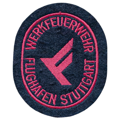 Abzeichen der Werkfeuerwehr Flughafen Stuttgart mit rotem Schriftzug auf dunklem Hintergrund.