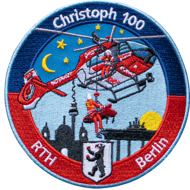Patch zeigt einen Hubschrauber mit Retter über Berlin bei Nacht.